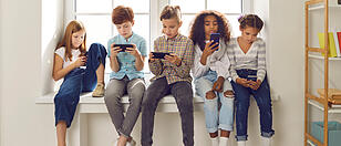 Children of different nationalities play online games or read social networks on mobile phones.