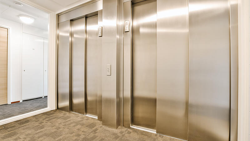 a row of stainless steel elevator doors in a hallway