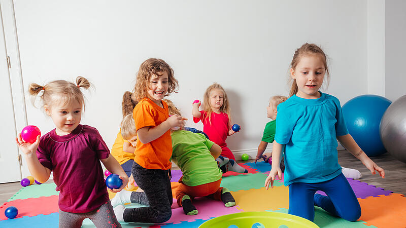 Happy kids throwing balls into plastic basket