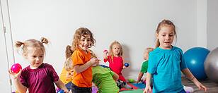 Happy kids throwing balls into plastic basket