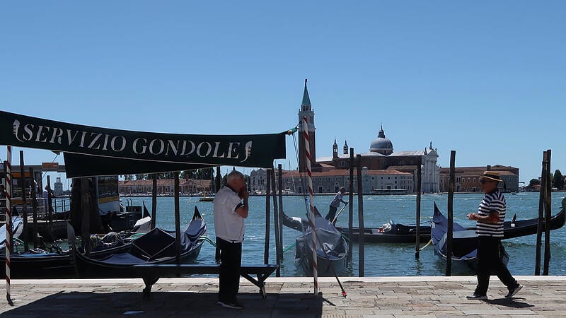 Gondoliers are pictured in front of San Giorgio Maggiore island in Venice