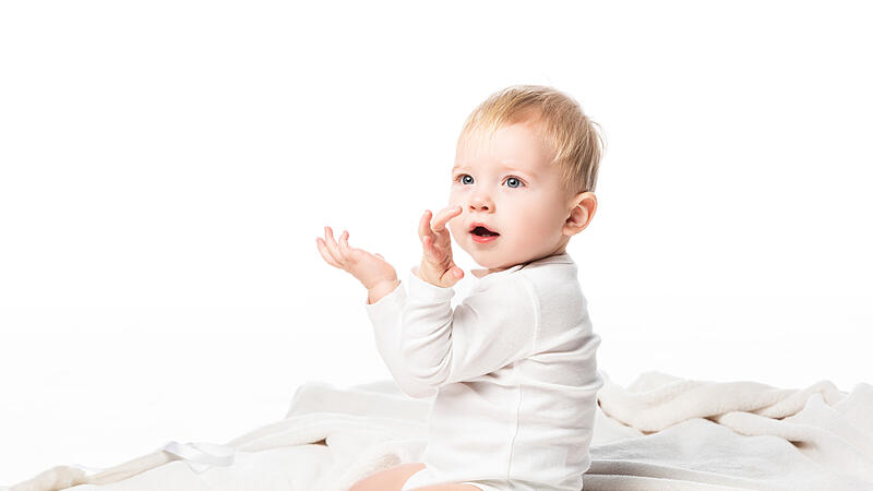 Side view of cute child kneeling with raised hands and open mouth isolated on white