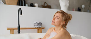 Young woman taking bath with foam bubbles at home bathroom