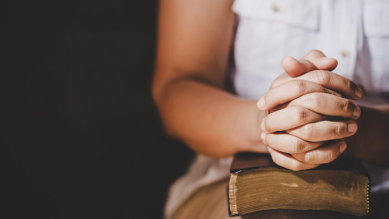 Spirituality and religion, Hands folded in prayer on a Holy Bible in church concept for faith.