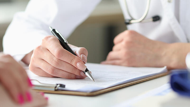 Hands of doctor writing in a patient medical card