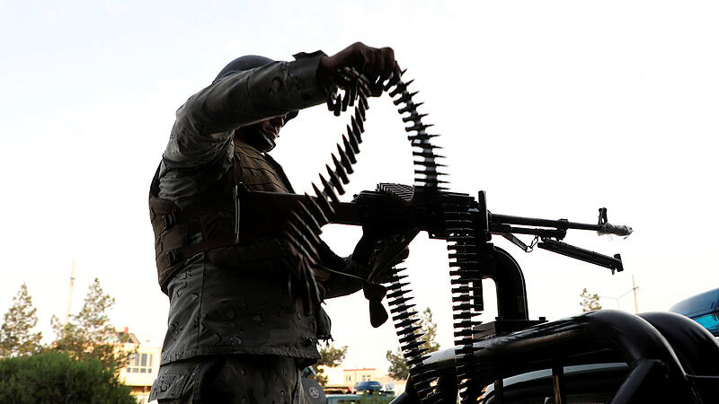 A member of Afghan security forces loads a machine gun near the site of a powerful blast in Kabul