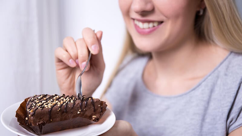 young smiling woman eating chocolate cake at home