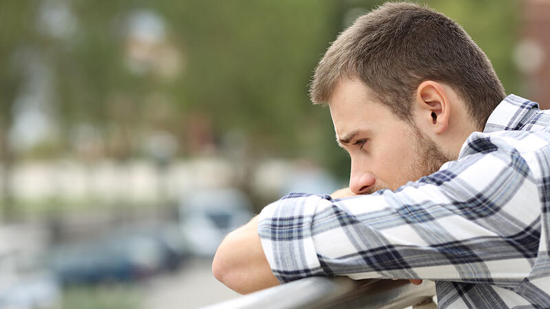 Sad man looking down from a balcony