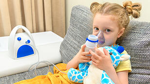 The child breathes with an inhaler together with a toy.