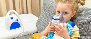 The child breathes with an inhaler together with a toy.