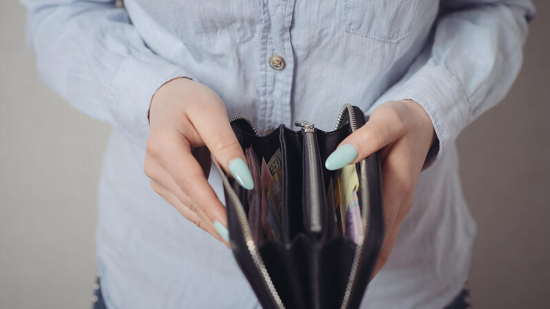 Close-up of women's purse in his hands. On a gray background.