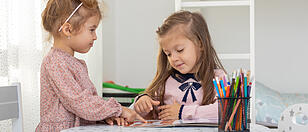 Cute children girls are reading a book in room at home. Two sister girls reading a book and having fun.