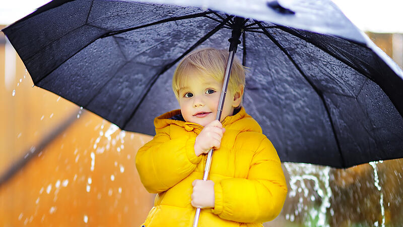 Child with big black umbrella in the rain