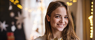 Happy young woman indoors at home at Christmas, holding present.