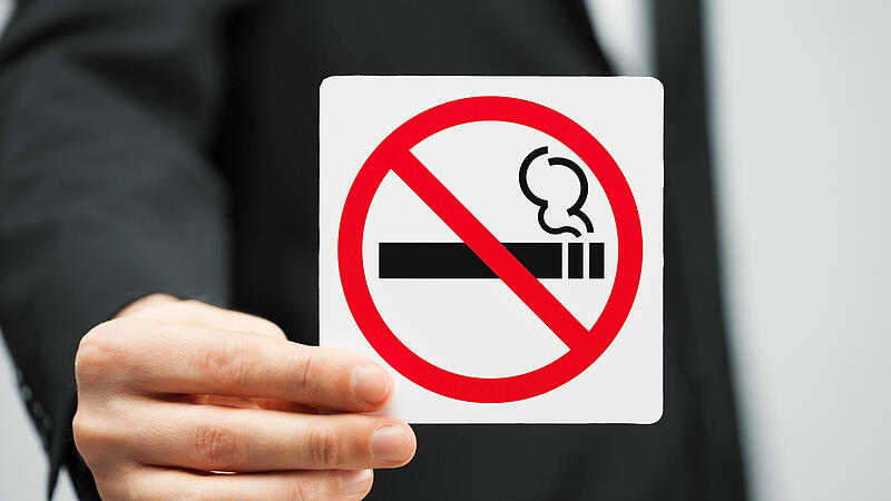 man in suit holding no smoking sign