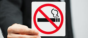 man in suit holding no smoking sign