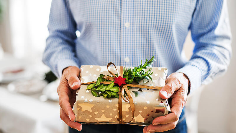 An unrecognizable senior man holding wrapped present at Christmas time.