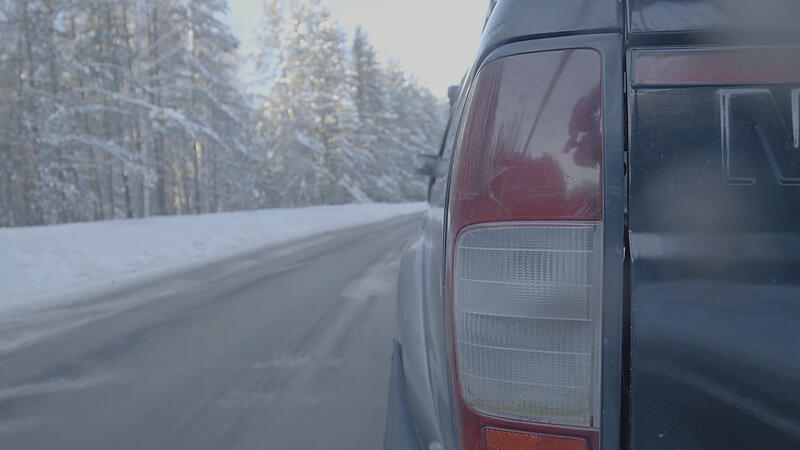 Headlight closeup on snowy roads. The car rides on a snow-covered road