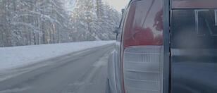 Headlight closeup on snowy roads. The car rides on a snow-covered road