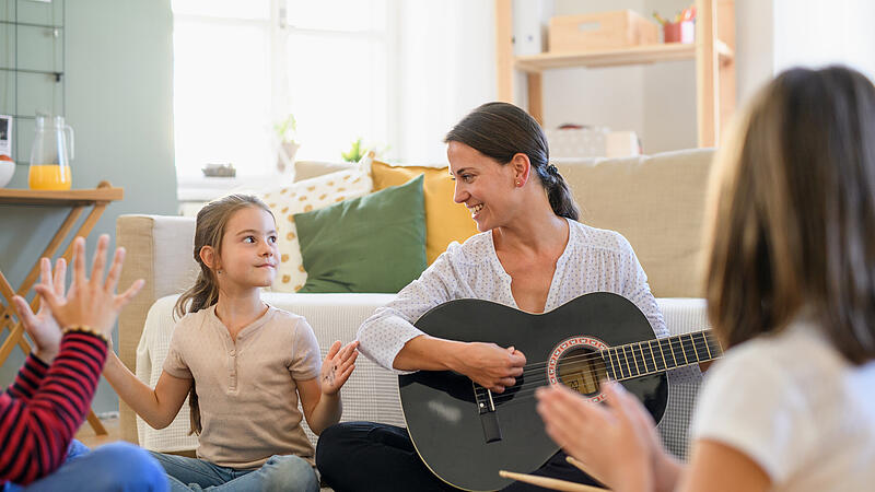 Group of homeschooling children with teacher having music lesson indoors, coronavirus concept.