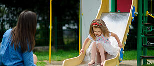 Mom and her little daughter are playing on the playground.