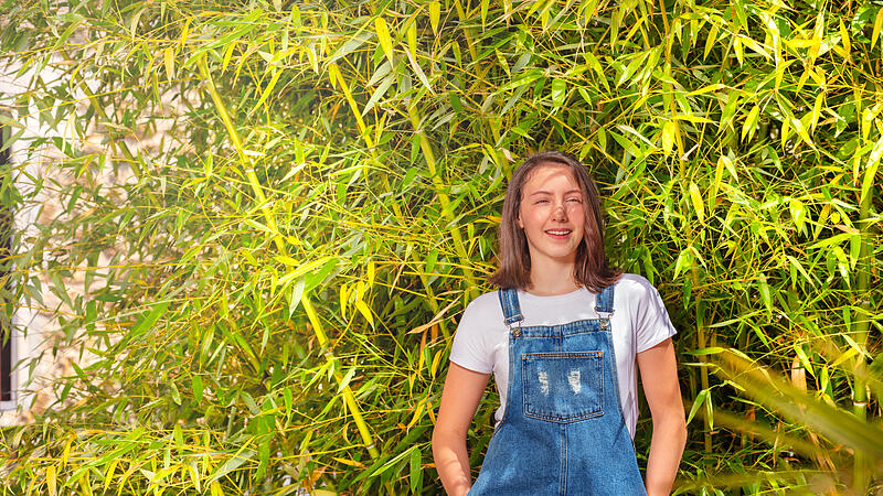 Smiling teenage girl against green bamboo bush