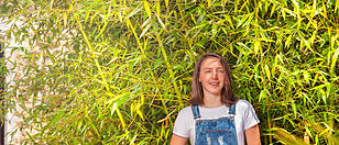 Smiling teenage girl against green bamboo bush